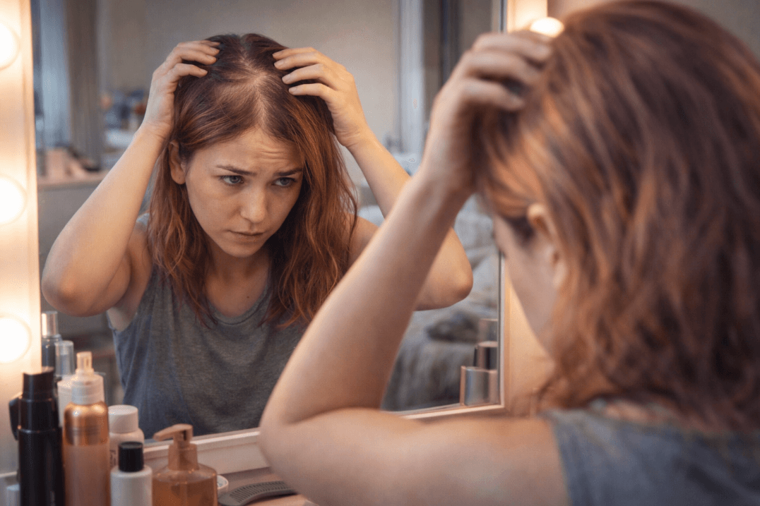 Woman examining thinning hair in mirror